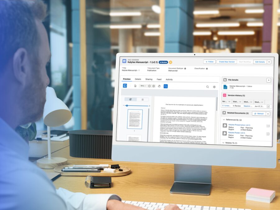 A person works at a desk using a desktop computer displaying a document management or editing software interface.