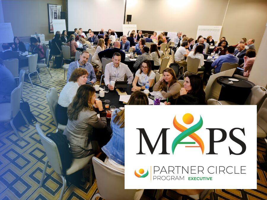 A large group of people sit at round tables in a conference room, engaging in discussion. In the foreground is a MAPS Partner Circle Program Executive logo.