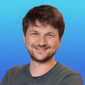 A man with short brown hair and a beard is smiling at the camera against a blue gradient background, representing the International Society for Medical Publication Professionals.