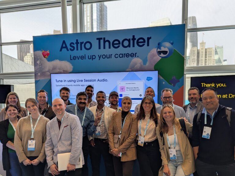 A group of people pose and smile for a photo in front of an "Astro Theater" sign at a professional event, with city buildings visible through large windows behind them.