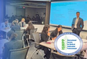 People seated at tables engage in group work in a conference room with a man standing by a projector screen. An ISMPP Silver Level Corporate Sponsor badge is displayed in the lower right corner.