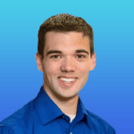 A man with short brown hair, wearing a blue collared shirt, smiles in front of a blue gradient background.